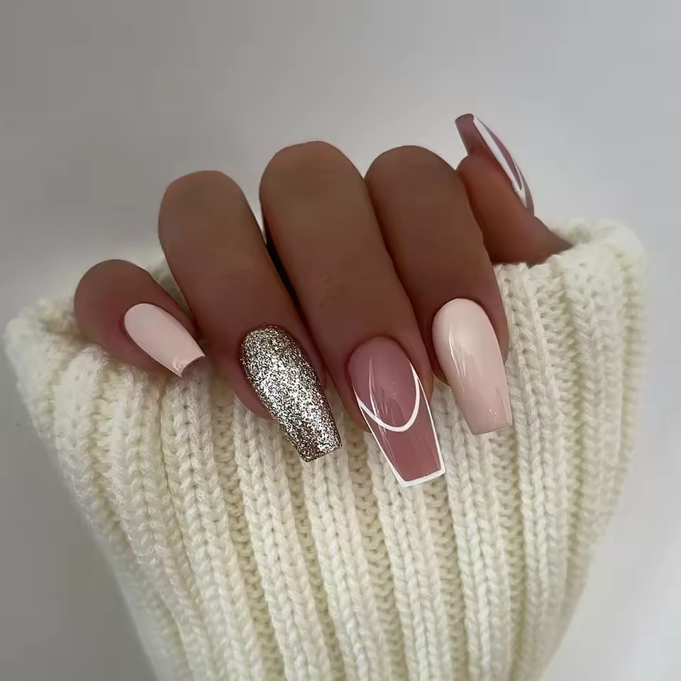 Minimalist coffin nails with nude bases, gold glitter, mauve accents, and white tips, showcasing a chic and elegant nail art design for 2025.