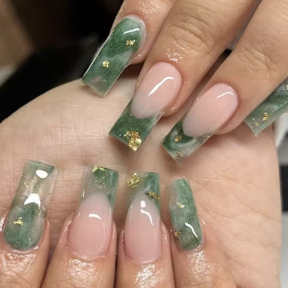 Luxurious coffin nails with a jade marble design, gold flakes, and nude base, showcasing an elegant and trendy nail art style for 2025.