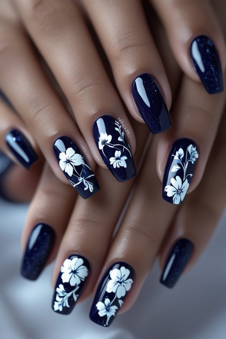 Midnight blue nails featuring intricate white flower designs on a matte finish.