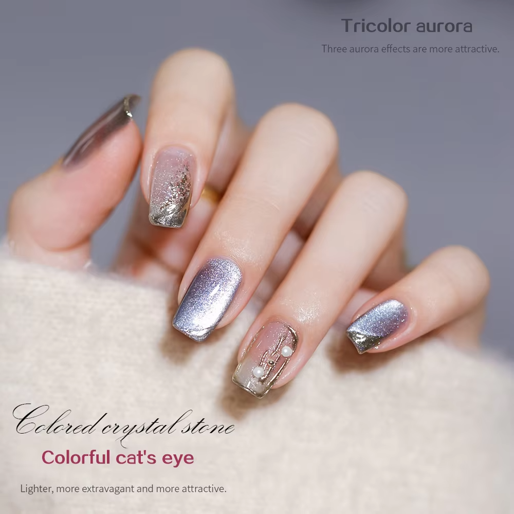 A close-up of a hand with tricolor aurora nail art, showing gradient colors, glitter, and decorative pearl-like beads.